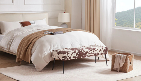Why might adding a small bench at the end of the bed make the bedroom feel more complete